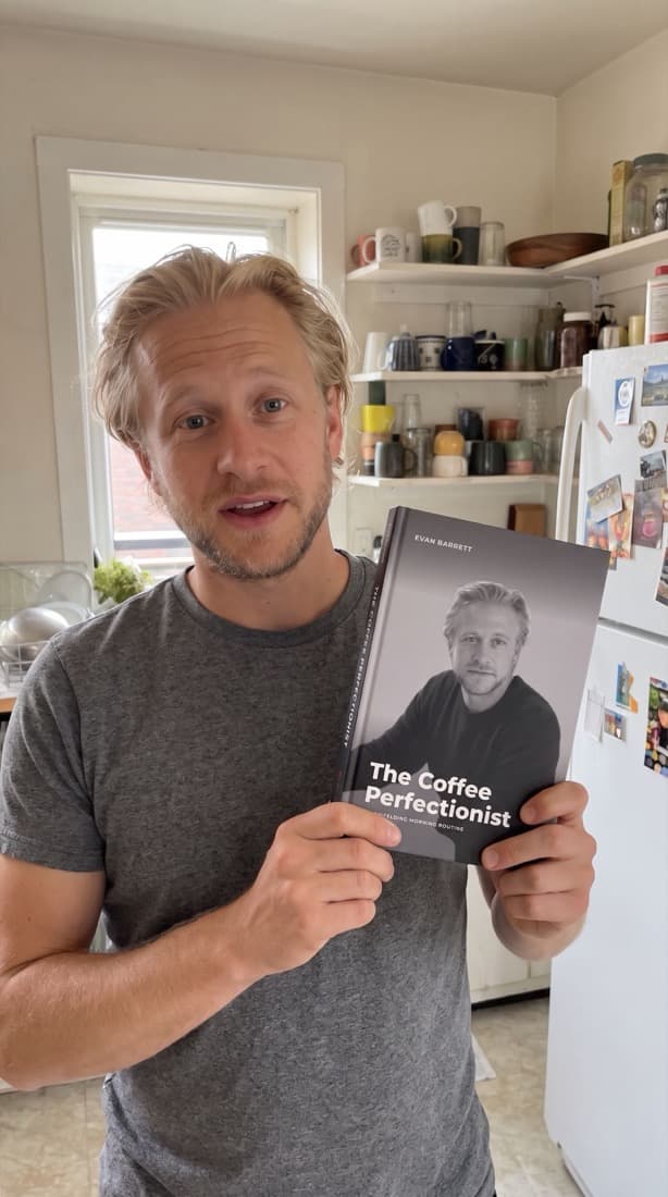 A man laughing as he holds up his personalized book, his portrait on the cover